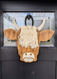 a door hanger with a cow's head made out of wood and rope