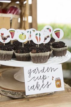 some cupcakes are on a white plate and there is a sign that says garden tips cakes