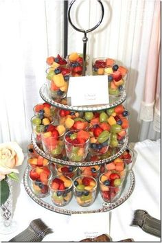 a tiered cake with lots of fruit on top and silverware next to it