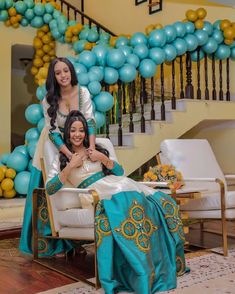 two women are posing for a photo in front of some balloons and decorations on the stairs