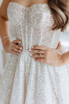 a woman in a white dress with her hands on her hip and wearing gold rings