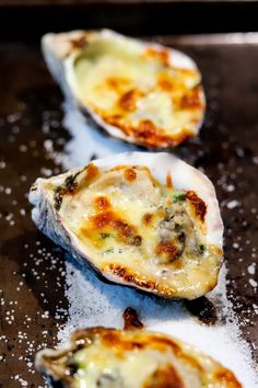 three open oysters sitting on top of a baking sheet covered in sea salt and seasoning