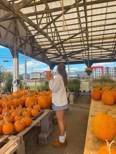 a woman standing in front of a bunch of pumpkins