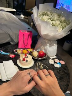 two hands on a table with flowers and jewelry