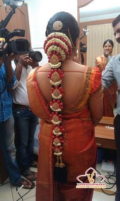 a woman in an orange sari is holding a camera