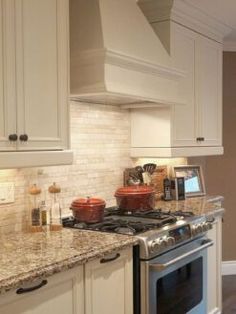 a stove top oven sitting inside of a kitchen next to white cabinets and counter tops