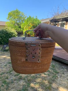 a person holding a wicker basket in front of a house on a sunny day