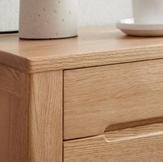 a close up of a wooden dresser with a cup on it's top and saucer next to it