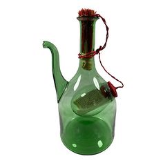 a green glass teapot with a brush in it's mouth and a red string hanging from the top