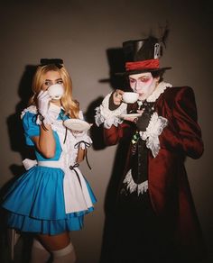 two people dressed up as alice and the mad hatter, one holding a tea cup