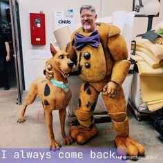 a man standing next to a dog wearing a costume