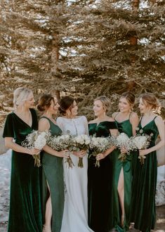 a group of women standing next to each other in front of some snow covered trees