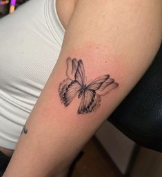 a woman's arm with a butterfly tattoo on the left side of her body