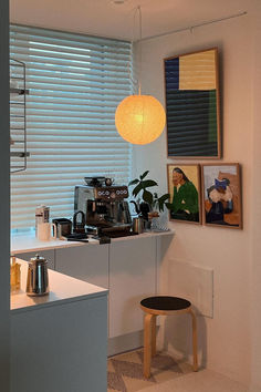 a kitchen area with a counter, stool and pictures on the wall