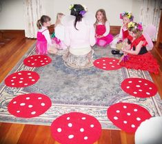 a group of children sitting on the floor in front of a rug with red and white polka dots