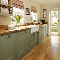 a kitchen filled with lots of green cabinets and counter top next to a wooden floor