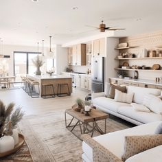 a living room filled with furniture next to a kitchen and dining room table in front of an open floor plan