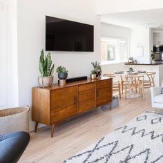 a living room filled with furniture and a flat screen tv mounted above a wooden cabinet