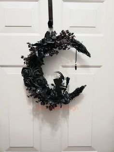 a halloween wreath hanging on the front door with black roses and bats around it,