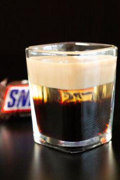 a glass filled with liquid sitting on top of a table next to a candy bar