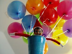 an elf is holding balloons in a blue cup with a toothpick sticking out of it