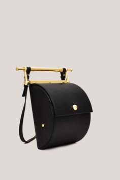 This is Thana. Handmade in Italy, using only the highest quality materials, Thana’s unique shape and gold-coated hardware make it an absolute stand-out. The brand’s signature decorative handle is undoubtedly unique, serving as both an intentional design detail and functional element to the bag. With an adjustable, removable strap the Thana can be styled cross-body, over the shoulder or as a chic handbag. Featuring our signature large interior compartment with pearl detail. Designer Gold Shoulder Bag With Brass Hardware, Office Satchel With Top Handle And Brass Hardware, Gold Satchel With Brass Hardware For Office, Office Gold Satchel With Brass Hardware, Modern Top Handle Satchel With Brass Hardware, Modern Satchel With Brass Hardware And Top Handle, Luxury Satchel With Brass Hardware, Modern Shoulder Bag With Brass Hardware, Modern Shoulder Bags With Brass Hardware