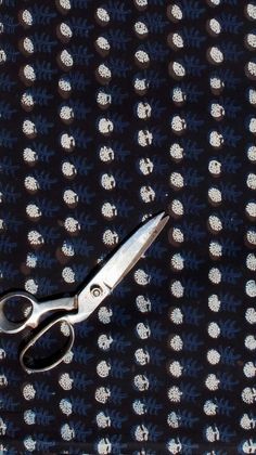 a pair of scissors sitting on top of a blue and white cloth with small dots