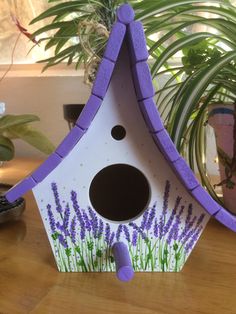 a birdhouse with purple flowers painted on it's side and the roof is made out of cardboard