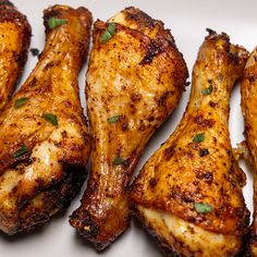 several pieces of chicken with herbs on the top and bottom of it, sitting on a white plate