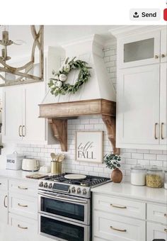 a kitchen with white cabinets and an open range hood over the stove, surrounded by greenery