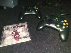 two video game controllers sitting next to each other on the floor with a dvd in front of them