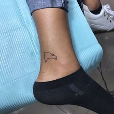 a person with a small tattoo on their ankle sitting in front of a blue suitcase