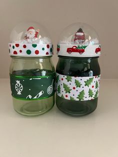 two jars with christmas decorations on them sitting next to each other