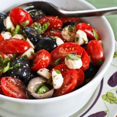 a white bowl filled with lots of different types of food on top of a table