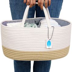 a woman holding a white basket filled with baby items on top of her stomach,