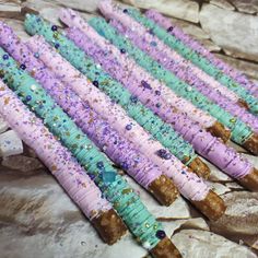 there are many purple and blue cake sticks on the table with sprinkles