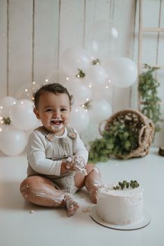 a baby sitting in front of a cake with frosting on it