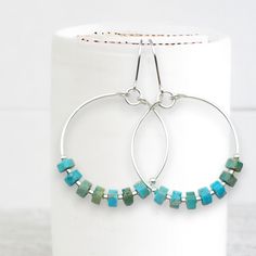 Add a pop of color to your boho look with our silver hoop earrings featuring turquoise jasper stones. These playful and unique earrings will bring a touch of whimsy to any outfit. .925 Sterling Silver Measure approximately 1.125" in diameter Earrings Hang 1.75" from top of ear wire Turquoise Jasper Gemstones Polished to a high shine Sent in a Gift Box with Polishing Cloth Handmade in Montana Turquoise Earrings With Silver Round Beads, Nickel-free Turquoise Dangle Hoop Earrings, Whimsical Turquoise Nickel-free Earrings, Southwestern Turquoise Nickel-free Hoop Earrings, Nickel-free Turquoise Southwestern Earrings, Turquoise Boho, African Turquoise, Jasper Stone, Boho Look