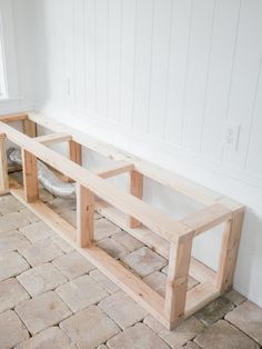 a wooden bench sitting on top of a stone floor next to a window sill