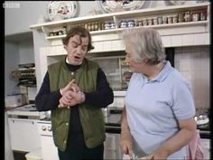 two people standing in a kitchen talking to each other