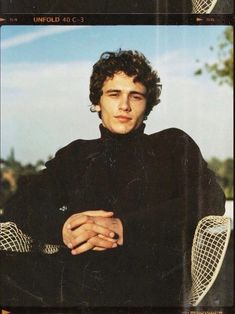 a young man sitting in a chair with his arms crossed