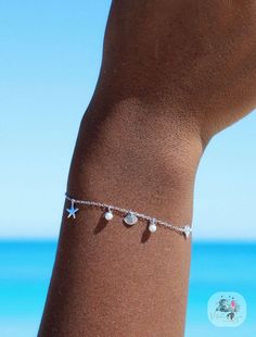 If you love the ocean as much as we do, you will fall in love with our Kula Kabana beachy bracelet. Decorated with shells, starfish and freshwater pearls this bracelet will remind you of the ocean where ever you go Our delicate yet detailed ocean inspired bracelet is truly made for mermaids. Never worry about taking it off with our 18k gold & sterling silver water safe jewelry Made with sterling silver & 18k gold vermeil - will never turn your skin green or tarnish Made with real ethically sourc Ocean-inspired Bracelet With Starfish Charm, Ocean-inspired Starfish Charm Bracelet, Summer Bracelets With Starfish Charm, Elegant Starfish Charm Jewelry For Vacation, Beach Jewelry With Silver Pearl Charm, Starfish Charm Bracelets For Beach Season, Silver Jewelry With Pearl Charm For Beach, Beach Jewelry: Silver With Pearl Charm, Silver Beach Jewelry With Pearl Charm