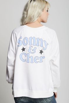 This sweatshirt is an absolute must have for any Sonny & Cher fan. The front features the duo's names and a photo graphic of the icons with their song "Bring It On Home To Me" below. "Sonny & Cher" is also featured on the back with stars. Made with vintage washed fabric, ribbed hems, a relaxed crew neckline, and an oversized fit. The design of this style is oversized. For a more standard fit, choose a size down. Details Style #302270 Color: White Sonny & Cher Bring It On Home To Me Oversized Swe White Screen Print Band Merch Sweatshirt, Graphic Print French Terry Crew Top, French Terry Crew Top With Graphic Print, Graphic Print Crew Top In French Terry, White French Terry Top With Graphic Print, Graphic Print Crew Neck Top In French Terry, White Oversized Band Merch Sweatshirt, White Letter Print Sweatshirt For Concert, White Band Merch Sweatshirt For Concerts