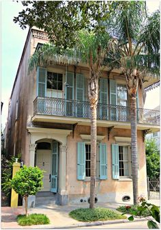 an old house with blue shutters and palm trees