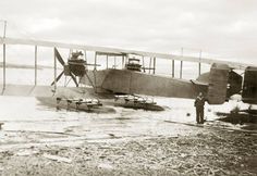 an old photo of two men standing in front of a plane that is on the ground