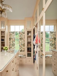 a large walk - in closet with lots of drawers and cupboards next to a chandelier