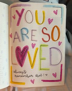 an open notebook with the words you are so loved written in colorful writing on it