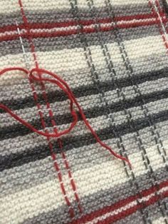 a close up view of a piece of fabric with a red heart on it and some thread