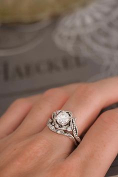 a close up of a person's hand with a diamond ring on their finger