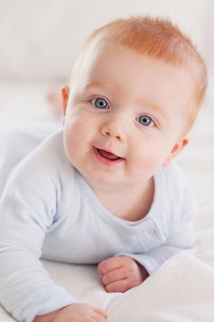 a smiling baby laying on top of a bed